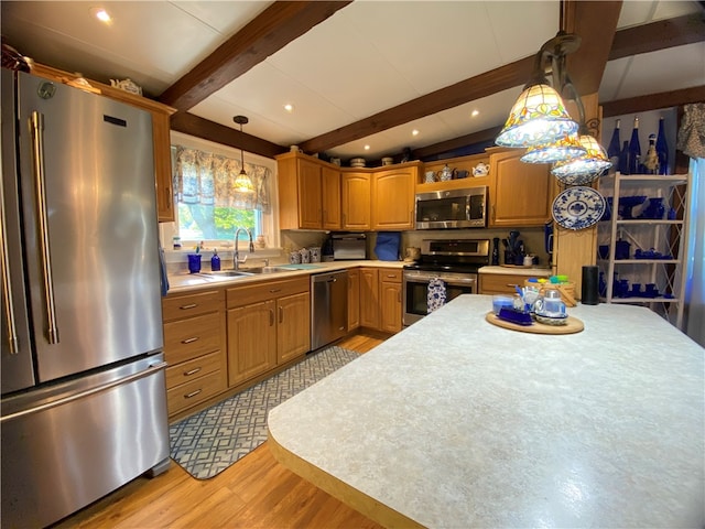 kitchen featuring appliances with stainless steel finishes, sink, beam ceiling, pendant lighting, and light hardwood / wood-style floors