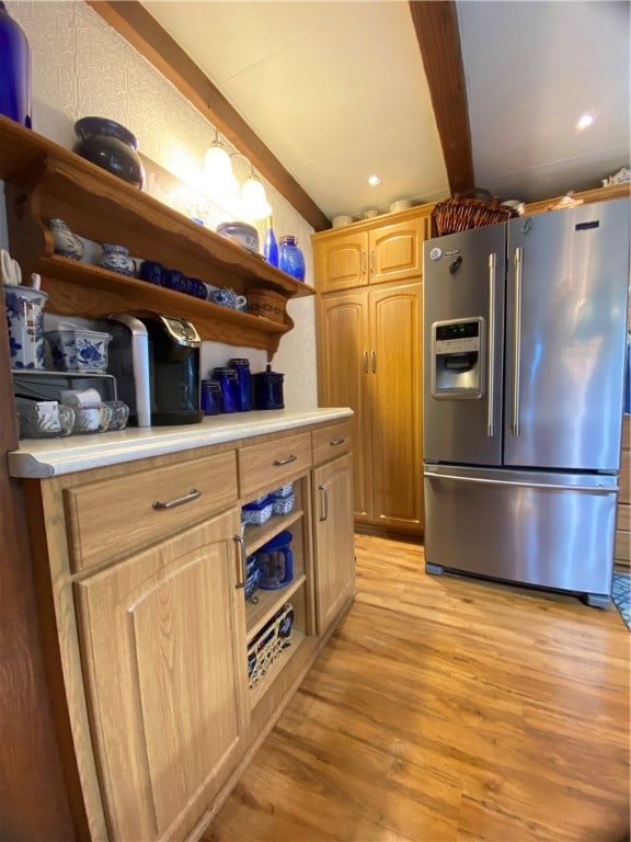 kitchen featuring beamed ceiling, light brown cabinets, light wood-type flooring, and stainless steel fridge with ice dispenser