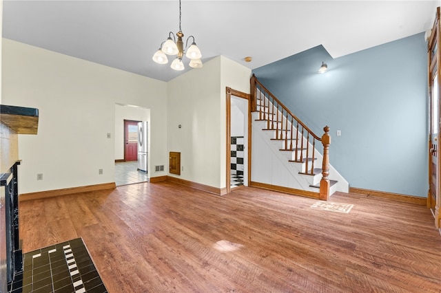 unfurnished living room featuring wood-type flooring and a chandelier