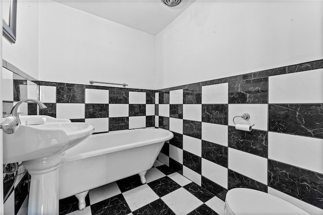 bathroom featuring tile walls, a tub, and toilet