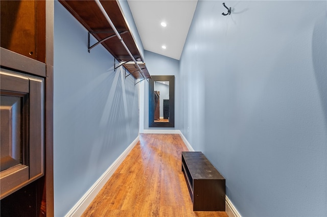 walk in closet with light wood-type flooring and vaulted ceiling