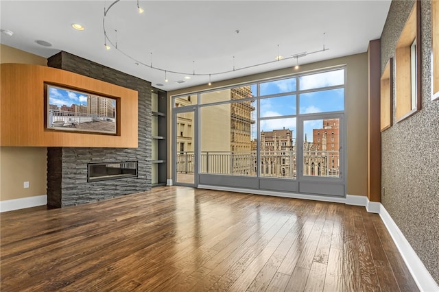 unfurnished living room featuring wood-type flooring, a fireplace, and rail lighting