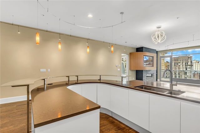 kitchen with pendant lighting, white cabinets, dark hardwood / wood-style floors, and sink