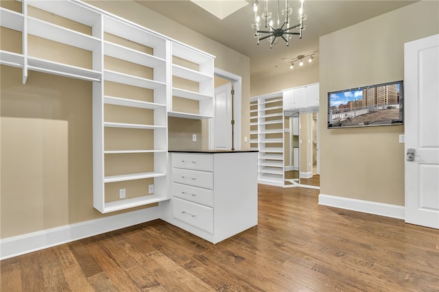 spacious closet featuring an inviting chandelier and wood-type flooring