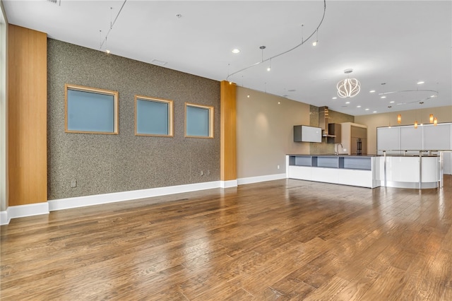 unfurnished living room with a chandelier, hardwood / wood-style flooring, and sink