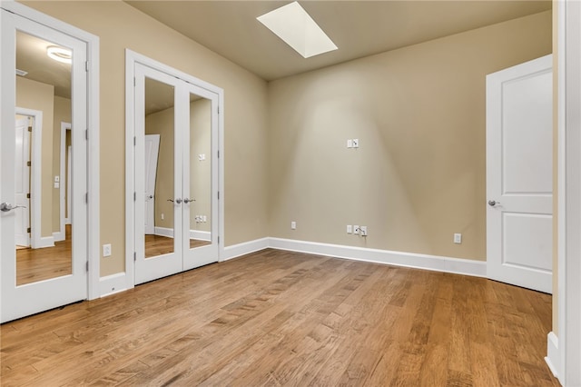 empty room with a skylight and light wood-type flooring