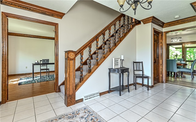 stairs with ornamental molding, hardwood / wood-style flooring, and a chandelier