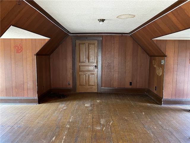 bonus room featuring lofted ceiling, wood walls, and dark wood-type flooring