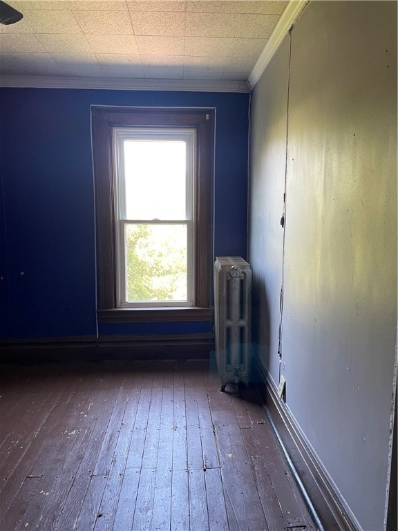 empty room featuring radiator, crown molding, and dark wood-type flooring