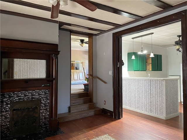 interior space with a tiled fireplace, ceiling fan, sink, and hardwood / wood-style flooring