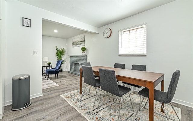 dining area with wood-type flooring and a fireplace