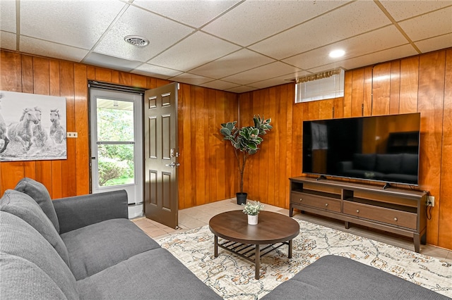 tiled living room featuring wooden walls and a drop ceiling