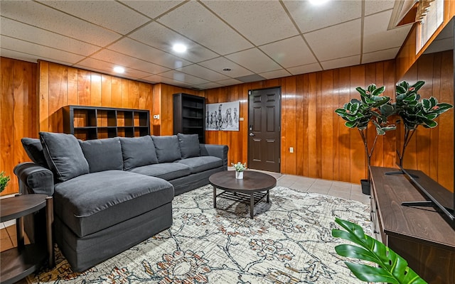 tiled living room with a drop ceiling and wooden walls