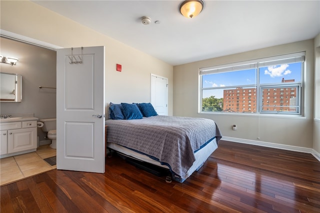 bedroom with ensuite bathroom, sink, and dark hardwood / wood-style flooring