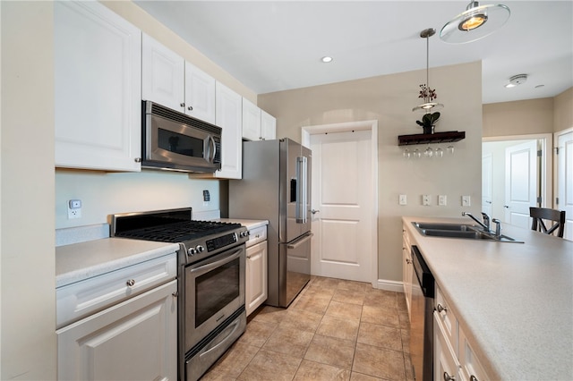 kitchen with light tile patterned floors, sink, high end appliances, decorative light fixtures, and white cabinetry