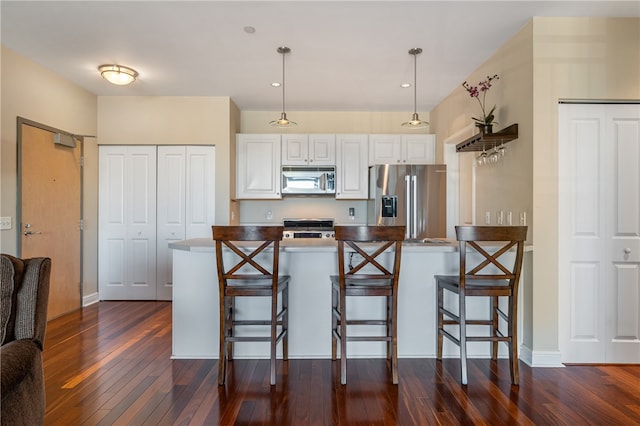 kitchen featuring pendant lighting, stainless steel appliances, white cabinetry, and dark hardwood / wood-style floors