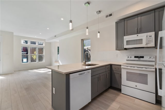 kitchen with sink, kitchen peninsula, white appliances, and a healthy amount of sunlight