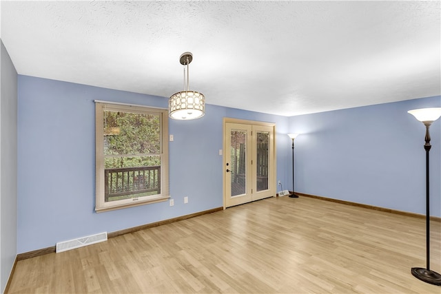 empty room featuring a textured ceiling and light hardwood / wood-style floors