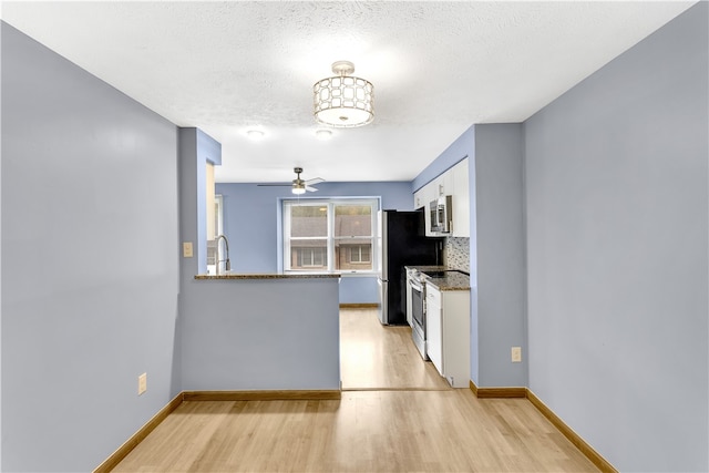 kitchen featuring appliances with stainless steel finishes, tasteful backsplash, white cabinets, ceiling fan, and light hardwood / wood-style flooring