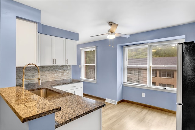 kitchen with stainless steel fridge, white cabinetry, backsplash, kitchen peninsula, and ceiling fan