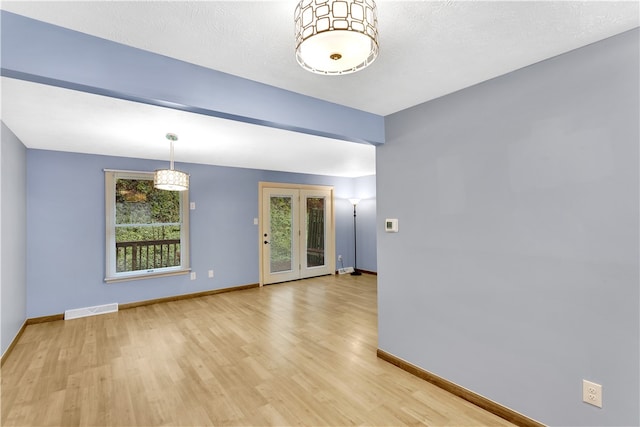 spare room featuring a textured ceiling and light hardwood / wood-style flooring