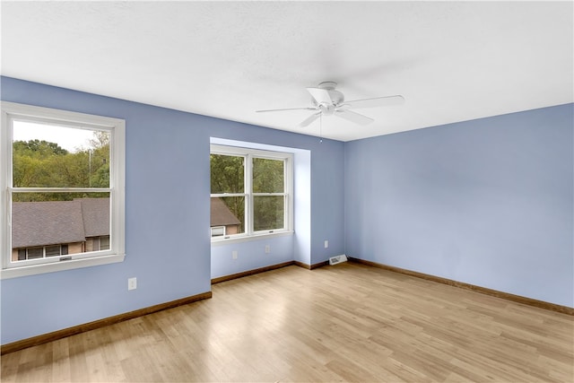 empty room featuring light hardwood / wood-style flooring, ceiling fan, and a healthy amount of sunlight