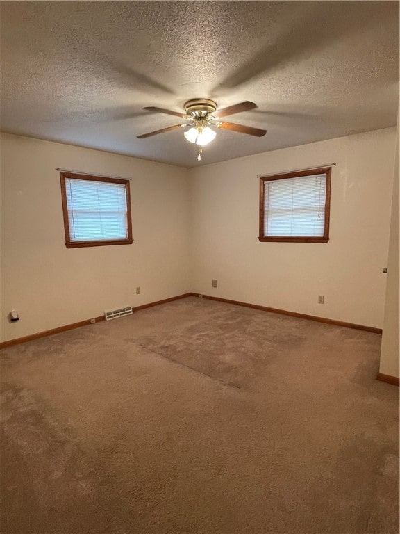 unfurnished room with a textured ceiling, carpet, and ceiling fan