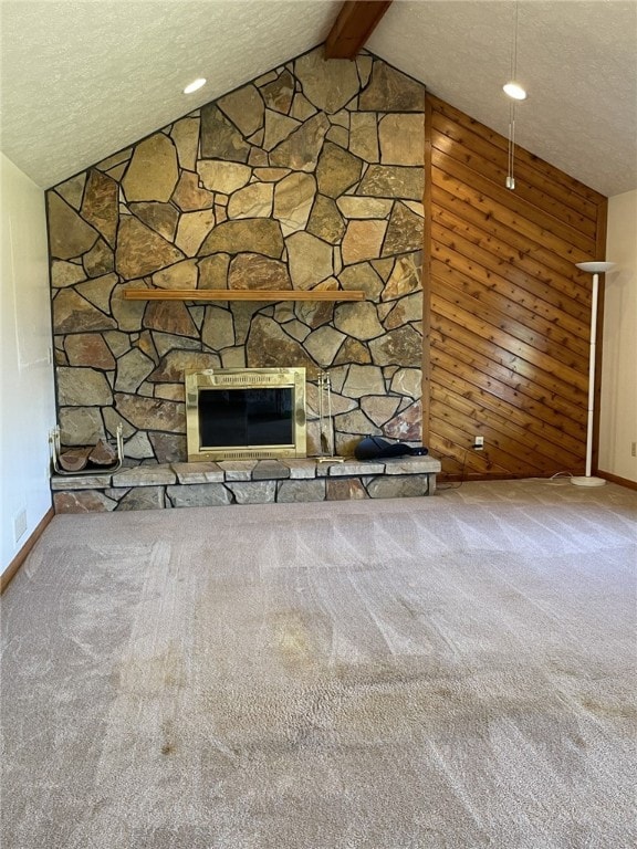 unfurnished living room with a textured ceiling, carpet floors, vaulted ceiling with beams, and a fireplace