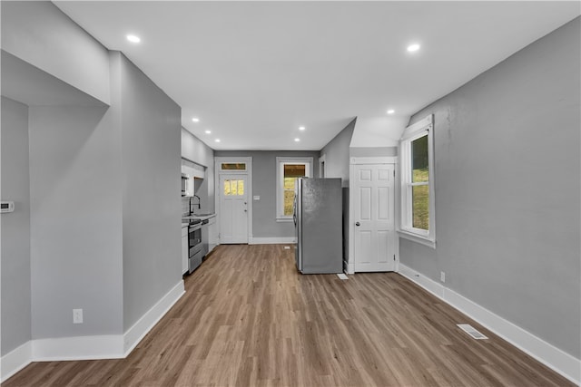 kitchen with appliances with stainless steel finishes, a healthy amount of sunlight, light hardwood / wood-style floors, and sink