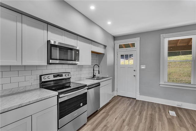 kitchen with a wealth of natural light, sink, stainless steel appliances, and white cabinets