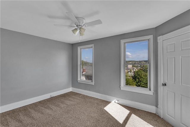 carpeted spare room featuring ceiling fan and plenty of natural light