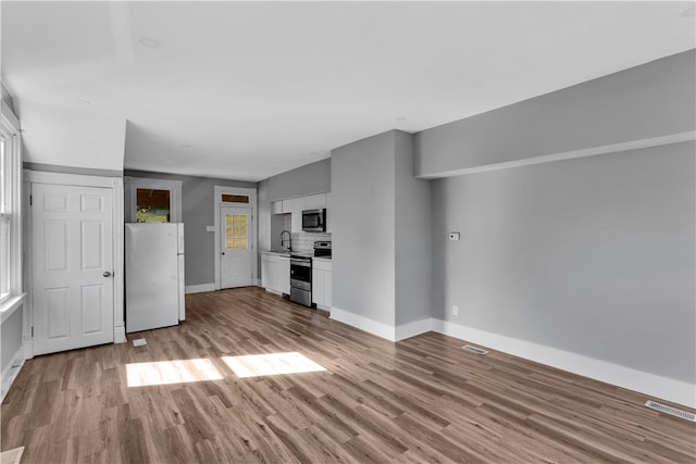 unfurnished living room featuring light wood-type flooring and sink