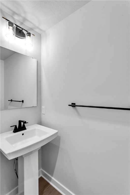 bathroom with wood-type flooring and a textured ceiling