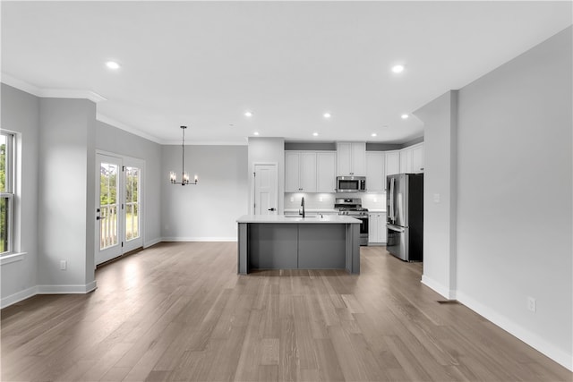 kitchen with light hardwood / wood-style flooring, a kitchen island with sink, white cabinetry, stainless steel appliances, and crown molding