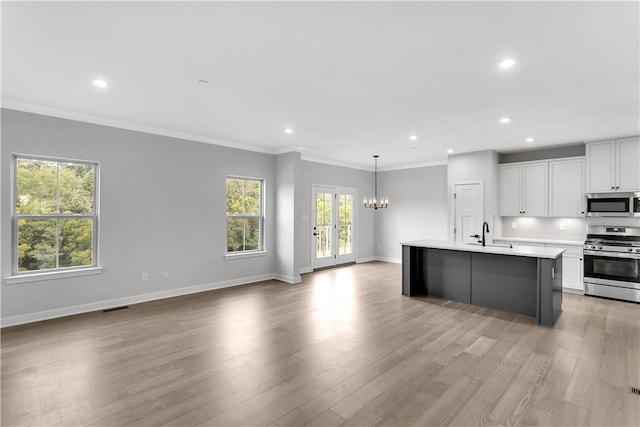 kitchen featuring a wealth of natural light, white cabinetry, a center island with sink, and appliances with stainless steel finishes