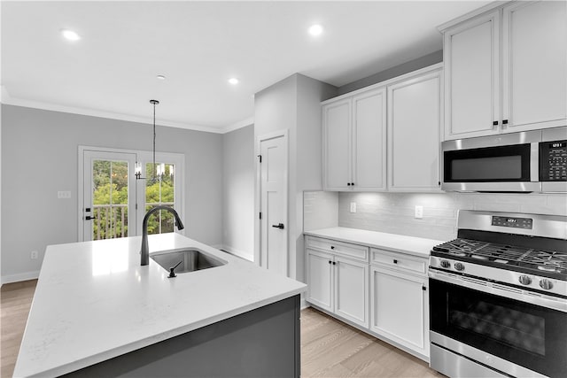 kitchen featuring appliances with stainless steel finishes, pendant lighting, light hardwood / wood-style flooring, a center island with sink, and sink