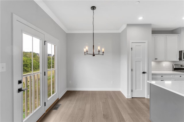 kitchen featuring decorative light fixtures, backsplash, a chandelier, white cabinetry, and light wood-type flooring