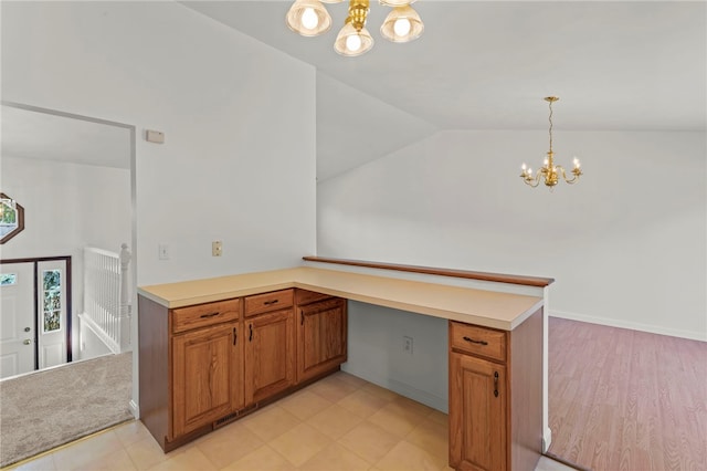 kitchen with pendant lighting, lofted ceiling, kitchen peninsula, light hardwood / wood-style flooring, and a chandelier