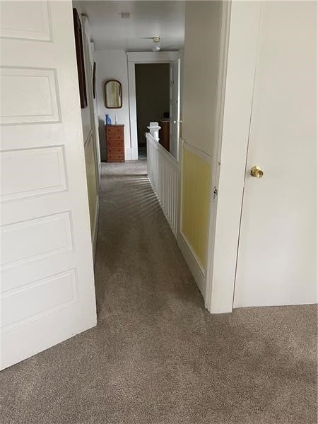 hallway featuring dark carpet