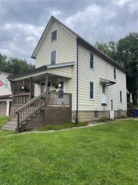 rear view of house featuring covered porch, a garage, and a lawn