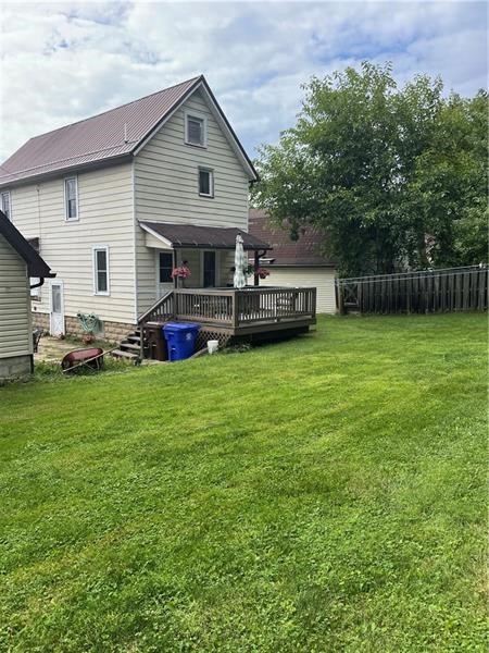 back of house with a deck and a yard