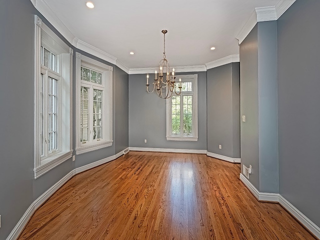 spare room featuring a notable chandelier, hardwood / wood-style flooring, and ornamental molding