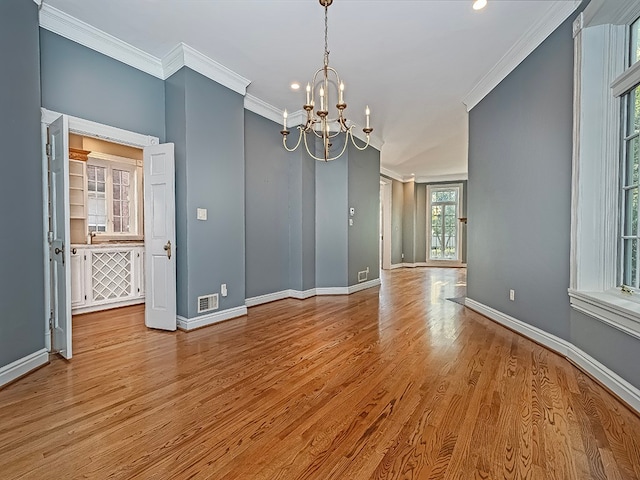 unfurnished room with light wood-type flooring, ornamental molding, a chandelier, and a wealth of natural light