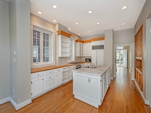 kitchen featuring light stone counters, light hardwood / wood-style flooring, a kitchen island with sink, white cabinetry, and appliances with stainless steel finishes