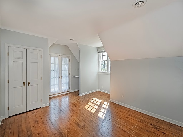 bonus room featuring light wood-type flooring, vaulted ceiling, and french doors