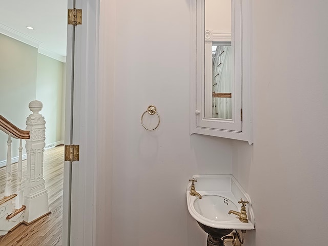 bathroom featuring wood-type flooring, sink, and ornamental molding