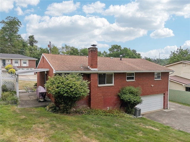 exterior space with a garage, central AC unit, and a yard