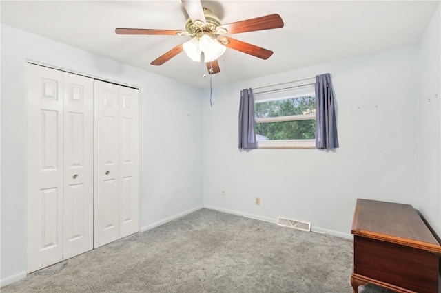 unfurnished bedroom featuring ceiling fan, light colored carpet, and a closet