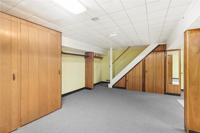 basement with light carpet and wooden walls