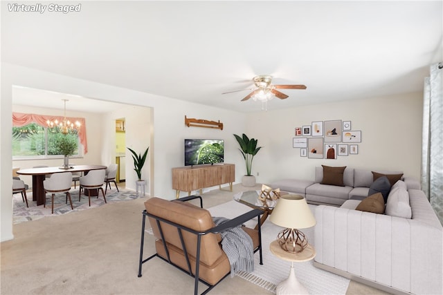 living room featuring light colored carpet and ceiling fan with notable chandelier